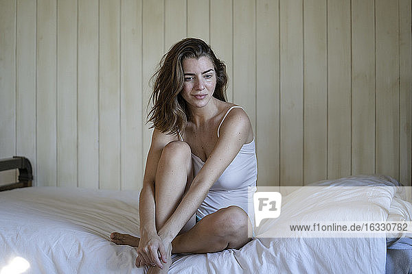 Beautiful young woman sitting on bed