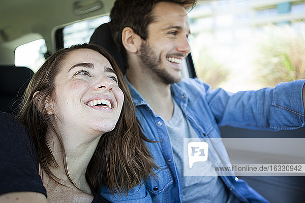 Fröhliches junges Paar hält Hände im Auto