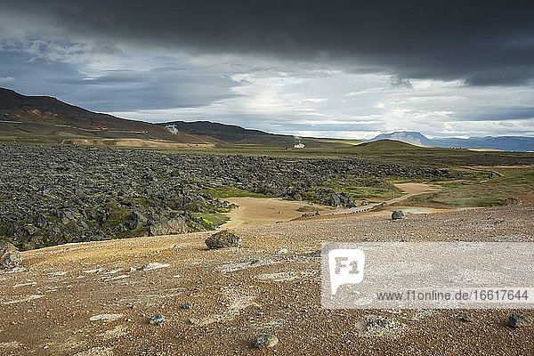 Black lava flow in Krafla lava field with geothermal power plant in the distance  Skútustaðir  Norðurland eystra  Iceland  Europe