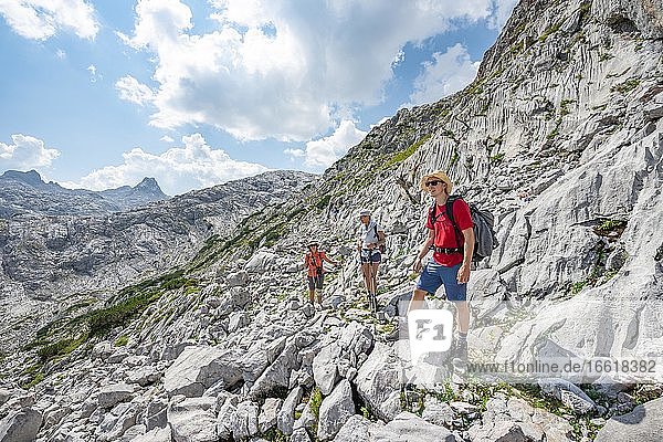 Three hikers in a landscape of washed-out karst rocks  Funtenseetauern  Steinernes Meer  Berchtesgaden National Park  Berchtesgadener Land  Upper Bavaria  Bavaria  Germany  Europe