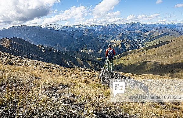 Hiker stands on stone  hiking trail to Ben Lomond  view of mountains  Southern Alps  Otago  South Island  New Zealand  Oceania