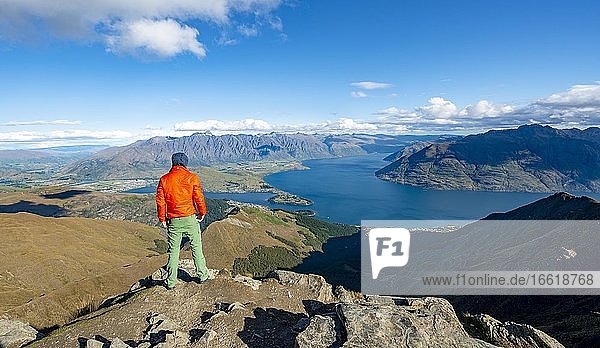 Hiker at the summit of Ben Lomond  views of Lake Wakatipu and The Remarkables mountain range  Southern Alps  Otago  South Island  New Zealand  Oceania
