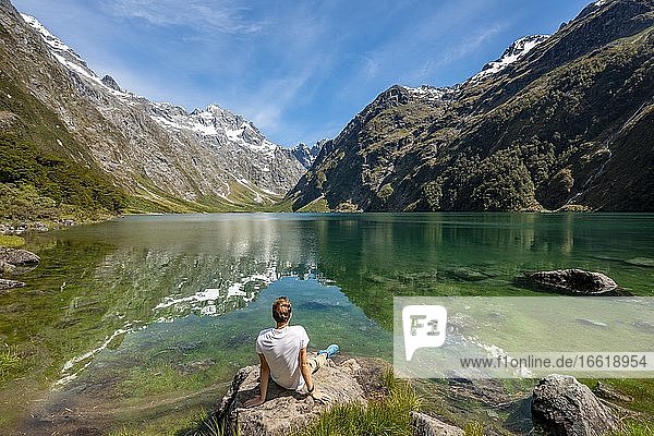 Hiker sitting on the shore  Lake Marian  Fiordland National Park  Te Anau  Southland  South Island  New Zealand  Oceania