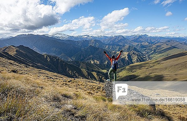 Wanderer streckt die Arme in die Luft  Wanderweg zum Ben Lomond  Ausblick auf Berge  Südalpen  Otago  Südinsel  Neuseeland  Ozeanien