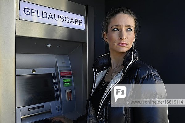 Frau steht vor Geldautomat einer Sparkasse  sieht sich um  Waiblingen  Baden-Württemberg  Deutschland  Europa