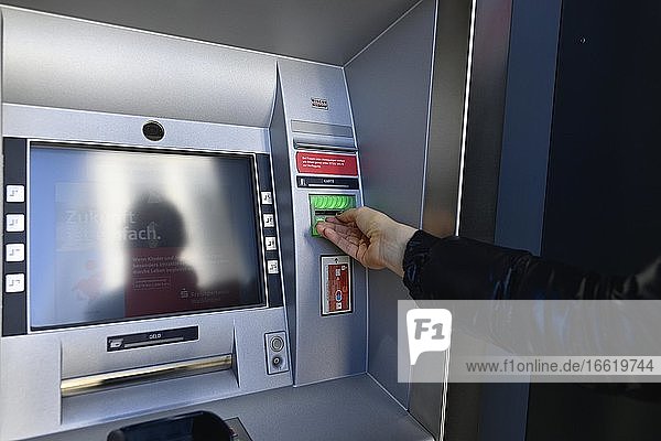 Frau wartet auf Ausgabe der ec-Karte am Geldautomat einer Sparkasse  Waiblingen  Baden-Württemberg  Deutschland  Europa