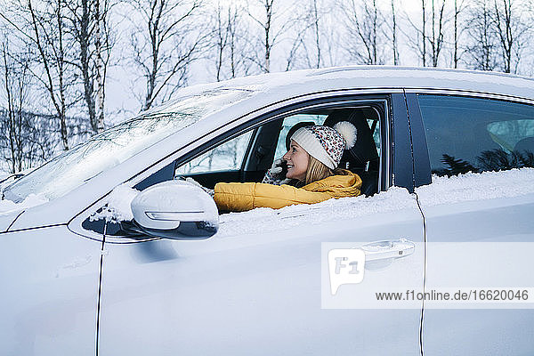 Reife Frau  die über ihr Smartphone spricht  während sie im Winter im Auto sitzt