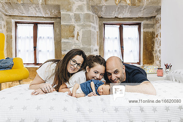 Smiling family lying on bed at home in bedroom