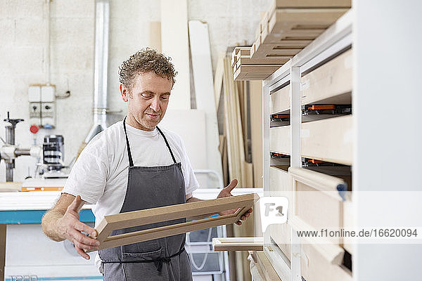 Carpenter holding frame while standing at workshop