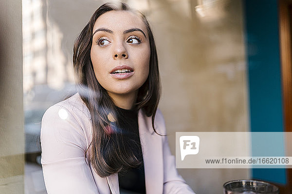 Junge Geschäftsfrau schaut weg  während sie in einem Café sitzt