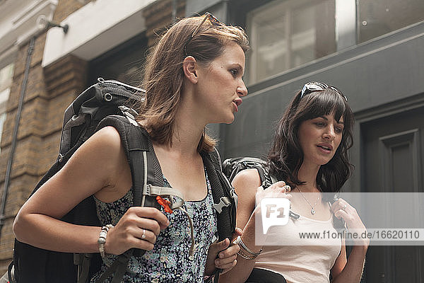 Beautiful female backpackers talking while walking in city
