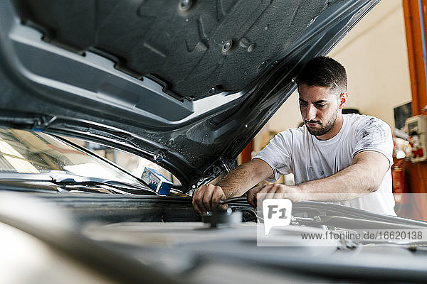 Junger Mann repariert Auto in einer Autowerkstatt