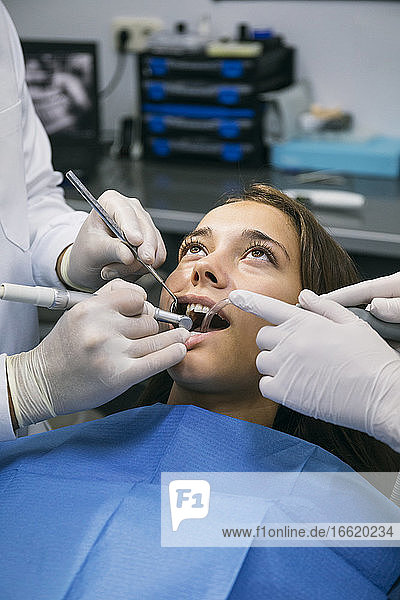 Zahnarzt in chirurgischen Handschuhen bei der zahnärztlichen Behandlung einer Patientin mit Hilfe einer Assistentin in der Klinik