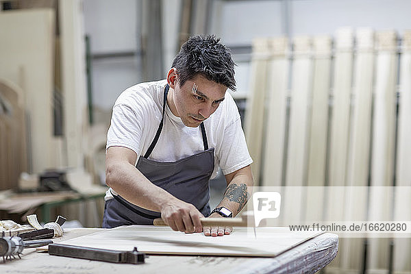 Künstlerin  die in der Werkstatt stehend Holz mit traditionellen Methoden gestaltet