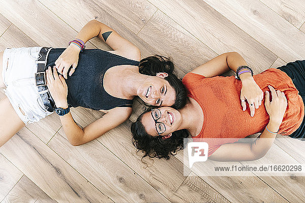 Friends smiling while lying down on floor at home