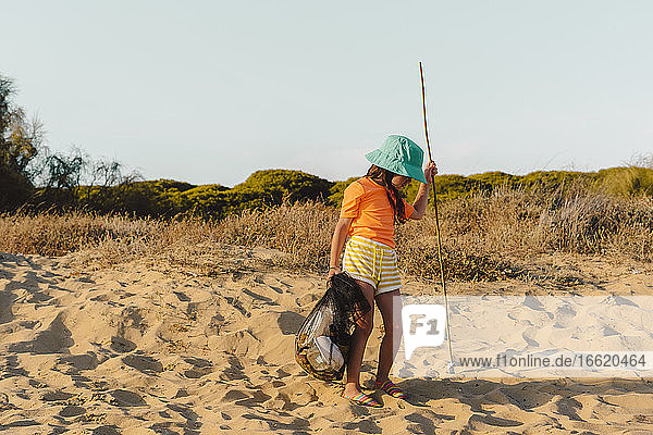 Mädchen  das Müll trägt  während es auf einem Ständer am Strand steht