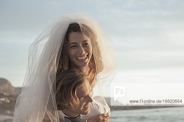 Frisch verheiratetes Paar in Hochzeitskleid genießen am Strand bei Sonnenuntergang