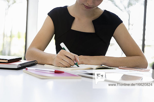 Close-up of fbusinesswoman writing on book at desk in office