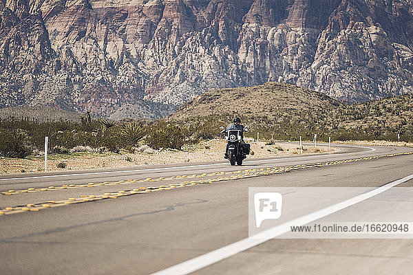 Man riding motorcycle on highway against mountain  Nevada  USA