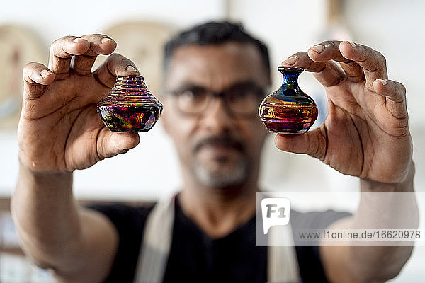 Nahaufnahme eines männlichen Künstlers mit Miniaturvasen in der Werkstatt
