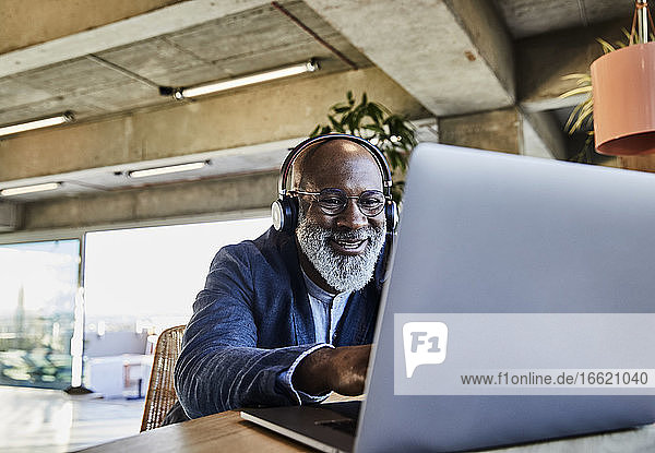 Geschäftsmann lächelnd bei der Arbeit am Laptop zu Hause
