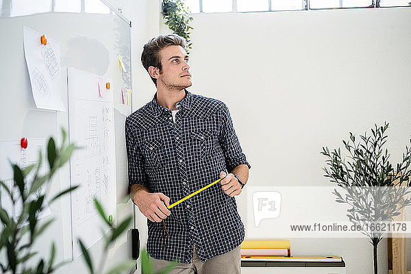 Thoughtful man leaning on whiteboard while standing at office
