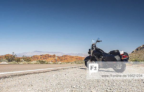 Motorrad  geparkt an einer Wüstenstraße gegen einen klaren blauen Himmel  Nevada  USA