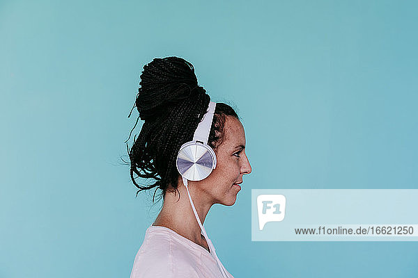 Schöne Frau hört Musik über Kopfhörer vor türkisfarbenem Hintergrund