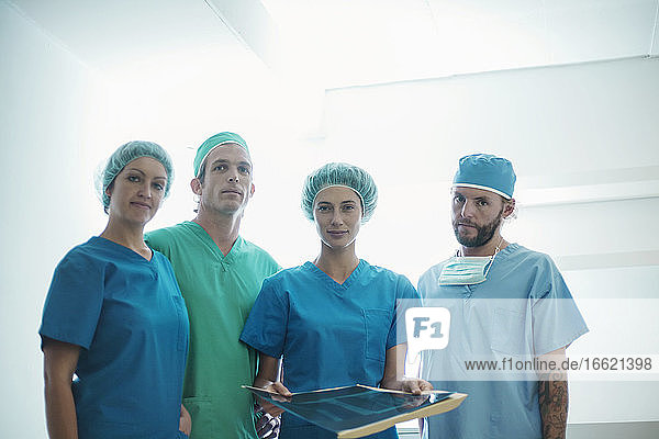 Selbstbewusstes Team von Chirurgen vor einem Röntgenbild im Krankenhaus