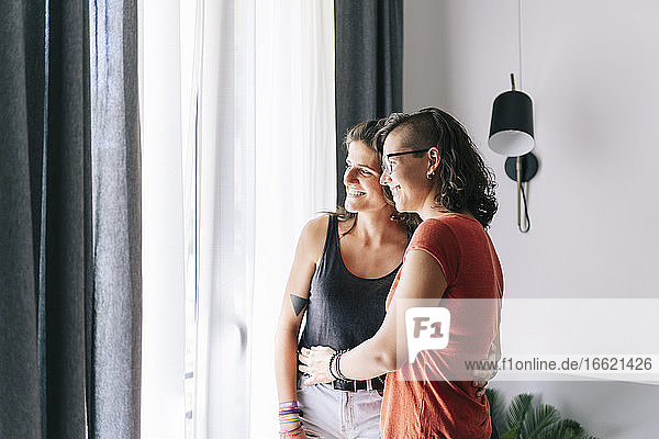 Friends looking through window while standing at home
