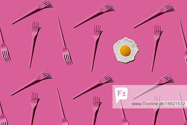Pattern of pink plastic forks with single fried egg