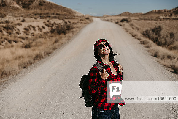 Spain  Navarre  Portrait of female tourist standing in middle of empty dirt road in Bardenas Reales