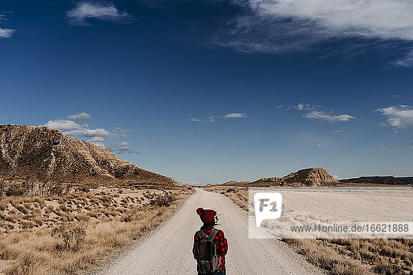 Spain  Navarre  Female tourist standing in middle of empty dirt road in Bardenas Reales