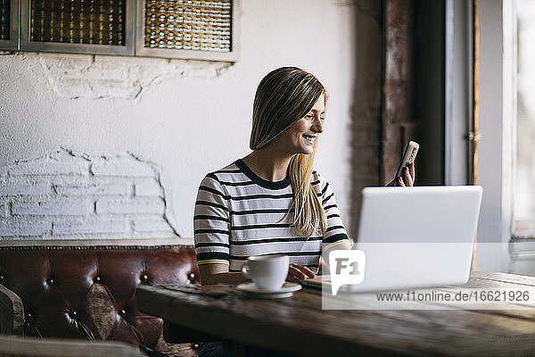 Mid erwachsene Frau Text-Messaging auf Smartphone beim Sitzen im Café