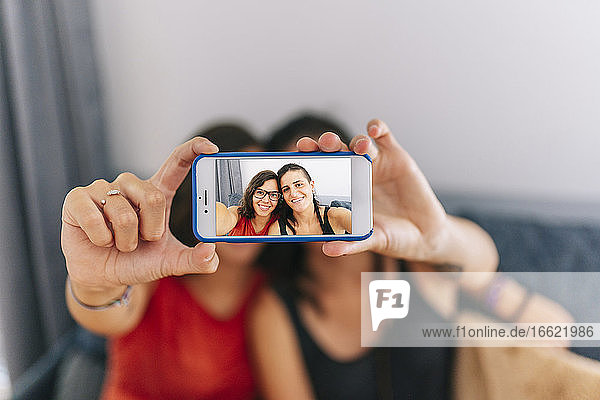 Weibliche Freunde machen ein Selfie mit dem Handy  während sie zu Hause sitzen