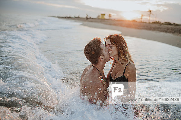 Couple doing romance while sitting in water at beach