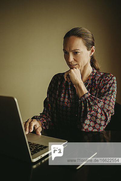 Geschäftsfrau  die im Büro sitzend am Laptop arbeitet