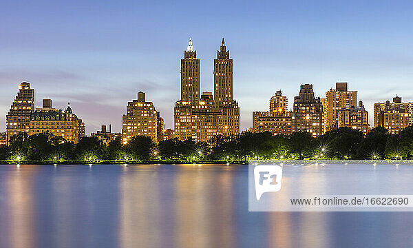 USA  New York  New York City  beleuchtete Gebäude der Upper West Side in der Abenddämmerung  gesehen über das Jacqueline Kennedy Onassis Reservoir