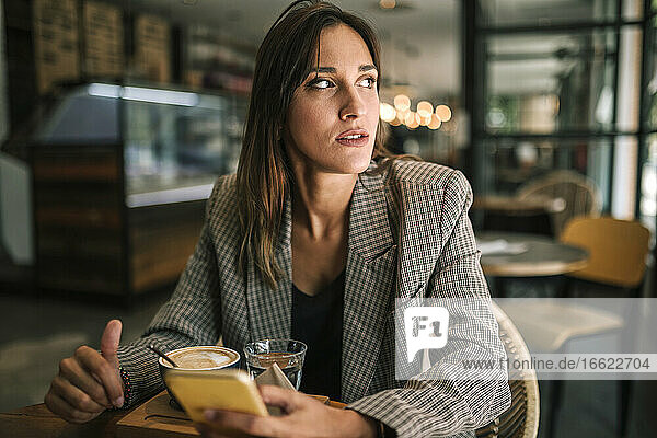 Junge Frau schaut weg  während sie in einem Café sitzt