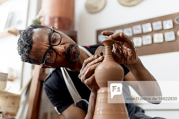 Nahaufnahme eines männlichen Künstlers bei der Herstellung von Steingut in einer Werkstatt