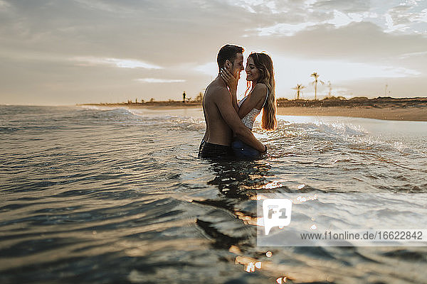 Romantic couple standing in water at beach