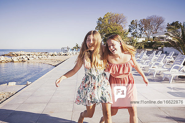 Freunde genießen beim Spaziergang auf dem Bürgersteig gegen das Meer