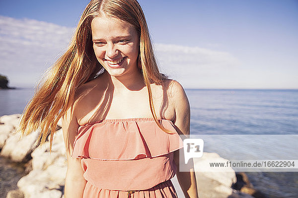 Teenager-Mädchen stehend gegen das Meer an einem sonnigen Tag