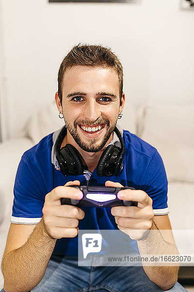 Lächelnder gut aussehender junger Mann  der zu Hause ein Videospiel spielt
