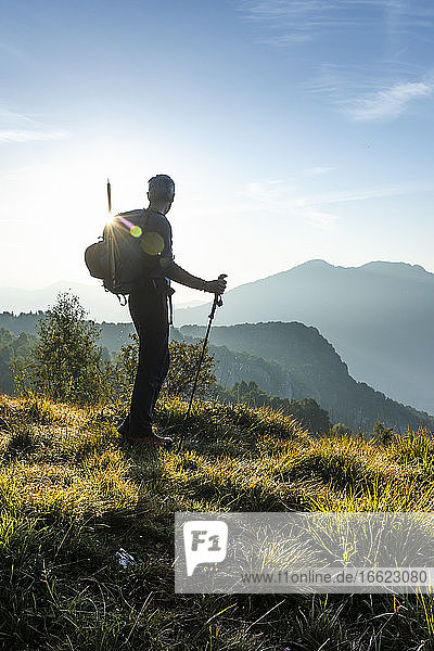 Silhouette male hiker looking at view while standing on mountain during sunrise  Orobie  Lecco  Italy