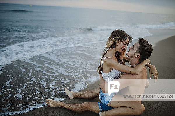 Junges Paar  das am Strand sitzt und eine Romanze hat
