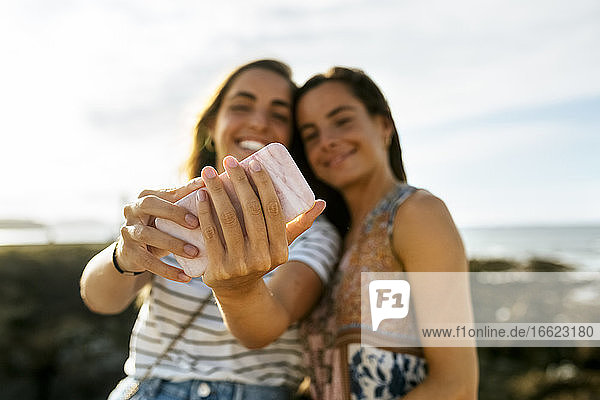 Glückliche junge Schwestern nehmen Selfie durch Smartphone am Strand während des Wochenendes