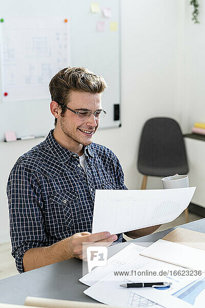 Architekt liest Dokument beim Kaffeetrinken im Büro
