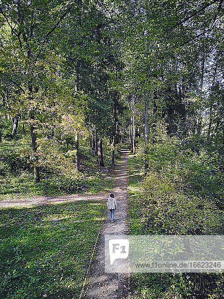 Frau geht auf dem Fußweg inmitten von Bäumen im Park