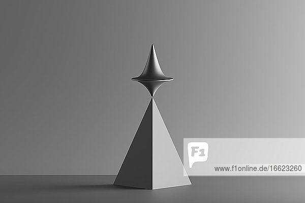 Dreidimensionales Rendering eines sich drehenden Metallkreisels auf einer geometrischen Pyramide